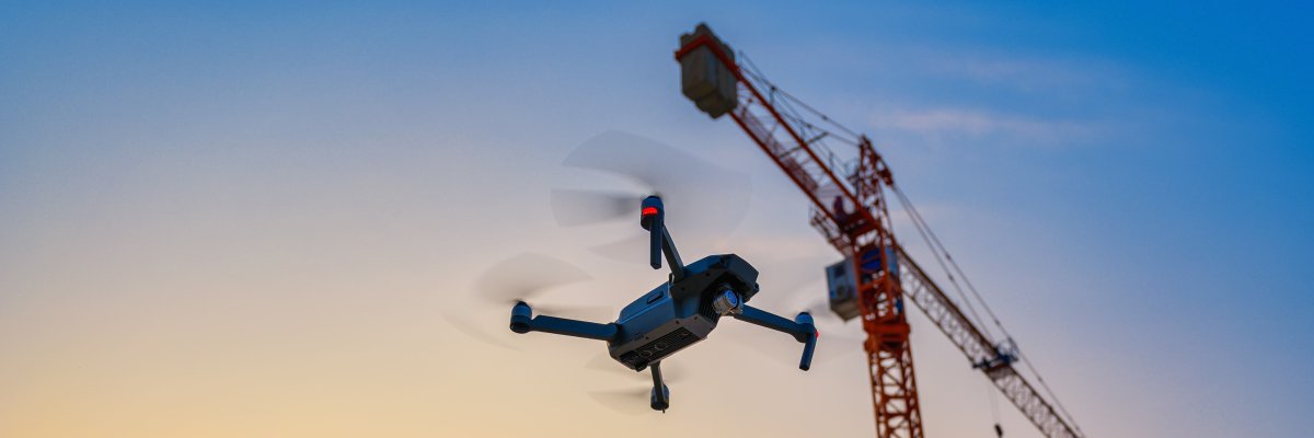 Eine Drohne fliegt neben einem Kran Titelbild: Eine Drohne fliegt neben einem Kran
